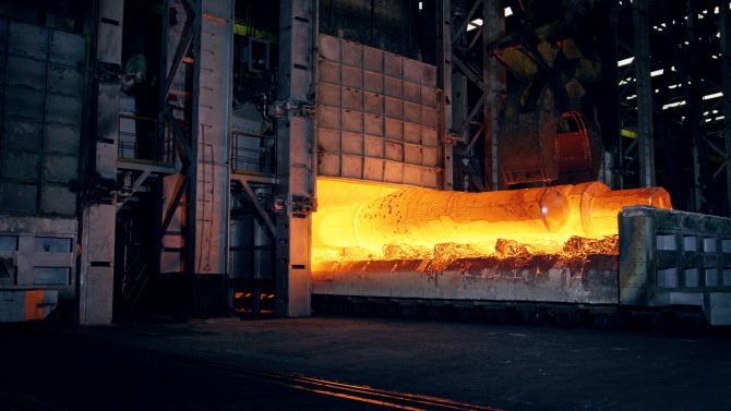 단조 프레스로 형상을 성형하기 위해 약 1100도로 달궈진 특수강 소재들이 가열로에서 이동되고 있다.