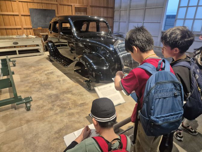 토요타자동차가 1936년 처음으로 시장에 출시한 ‘AA형 승용차’ 복각 모형 앞에서 일본 초등학생들이 모여있다. (사진=이윤화 기자)