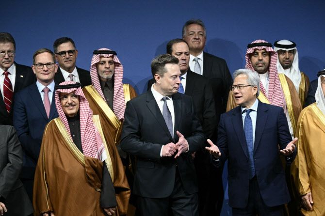 19일(현지시간) 미국 워싱턴 DC의 케네디센터에서 열린 미·사우디 투자 포럼에서 젠슨 황 엔비디아 최고경영자(CEO·오른쪽)와 일론 머스크(가운데)테슬라 CEO가 단체 사진 촬영 자리에서 논의를 하고 있다. (사진=AFP)