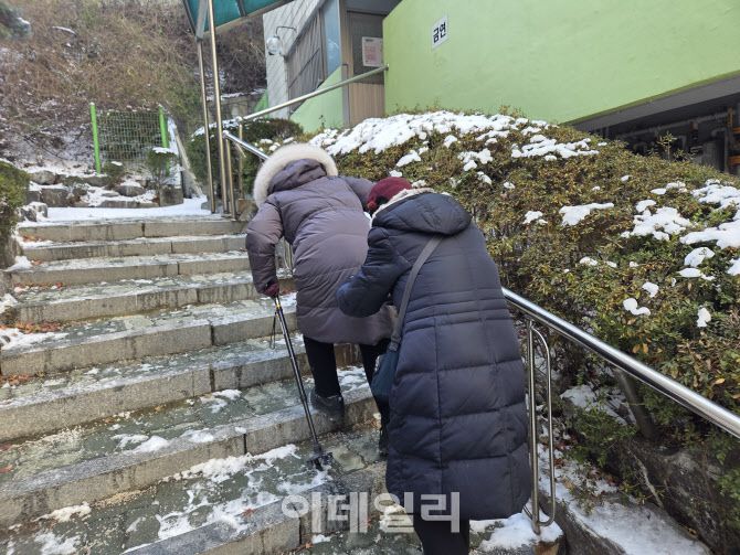 5일 서울 종로구 창신동의 한 아파트 단지 내에 있는 경로당을 가기 위해 서순심(90)씨가 동생의 부축을 받아 계단을 오르고 있는 모습이다. (사진=염정인 기자)