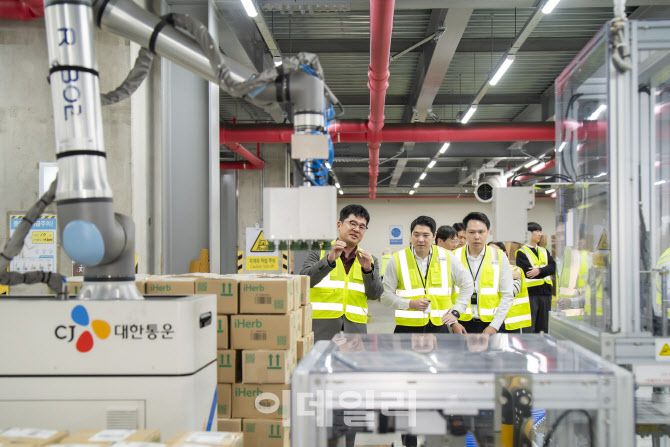 CJ대한통운 인천 GDC를 방문한 태국 최대 유통사 CP 엑스트라 경영진들이 박스를 자동 분류해 파렛트에 쌓는 ‘이동형 로봇 팔레타이저’에 대해 설명을 듣고 있다. (사진=CJ대한통운)