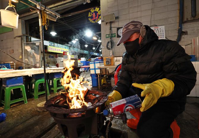 서울의 체감 온도가 영하 20도까지 떨어지는 등 전국 곳곳에 한파 특보가 발효 중인 26일 오전 서울 송파구 가락농수산물종합도매시장에서  한 상인이 불을 때고 있다. (사진=연합뉴스)
