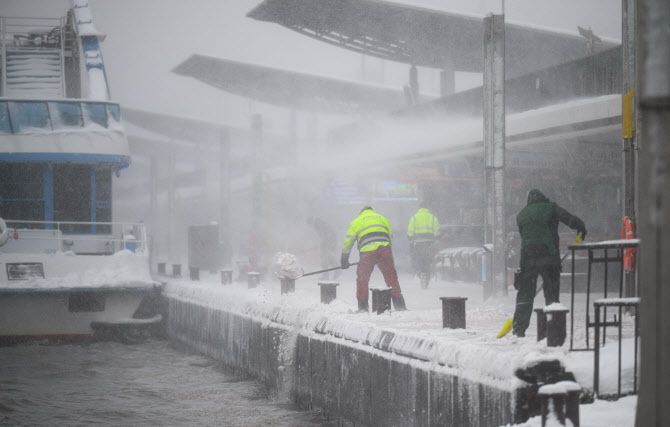 9일(현지시간) 독일 함부르크의 란둥스브루에켄에서 폭설이 내리는 동안 작업자들이 눈을 치우며 엘베 강으로 밀어내고 있다.(사진=AFP)