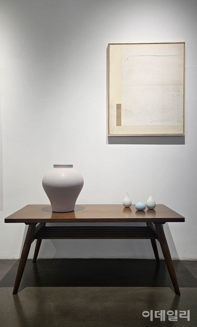 갤러리조은 ‘평온의 가장자리’ 전 전경. 작가 성연화의 작품과 조우한 조원재의 작품들이 2인전의 특별한 풍경을 만들어내고 있다. 탁자 위에 설치한 조원재의 작품 ‘분홍빛 호’(2023, 30×30×33㎝·왼쪽)와 ‘매우 작은 순간의 가장자리’(2025) 연작 위로 성연화의 한지회화 ‘평온’(Serenity 2025)이 걸렸다(사진=오현주 문화전문기자).