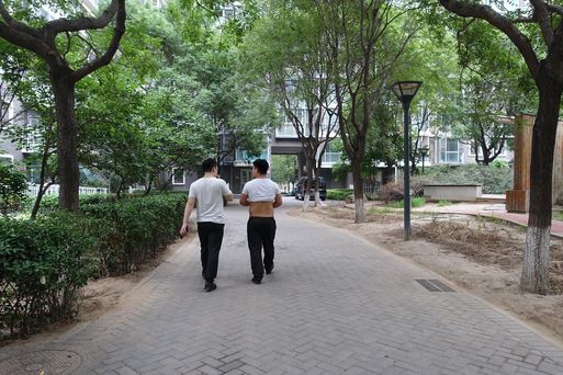 2019년 7월 20일 중국 베이징의 아파트 단지에서 한 남성이 흰색 티셔츠를 올린 채 배와 등을 내놓고 걷고 있다. 중장년층 남성뿐만 아니라 젊은 ‘방예’들도 자주 눈에 띈다. /베이징=김남희 특파원