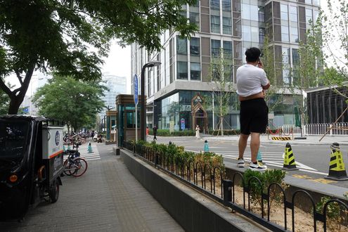 2019년 7월 19일 중국 베이징의 오피스 단지에서 한 남성이 흰색 티셔츠를 올린 채 배와 등을 내놓고 전화 통화를 하고 있다. /베이징=김남희 특파원