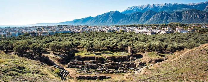 옛 스파르타의 고고학 유적지에 서면 험준한 타이게투스 산맥을 배경으로 현대 스파르타 시의 도심이 보인다. 사진 속의 토대뿐인 극장 터가 그나마 고고학 유적지에서 가장 잘 보존된 곳이다.