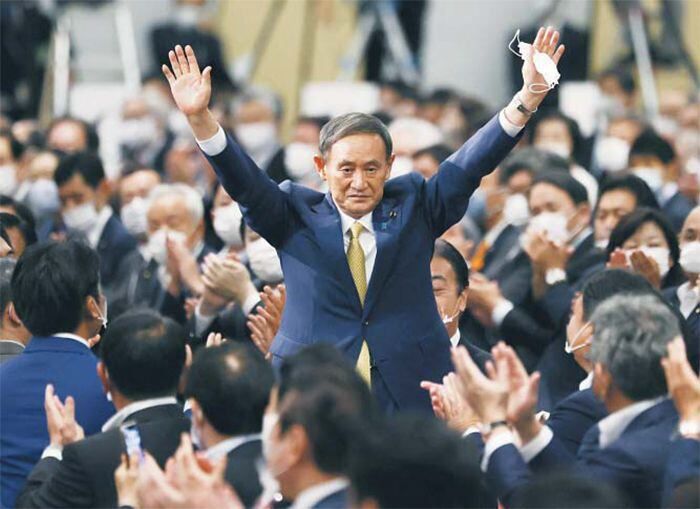 양손 치켜든 스가 - 스가 요시히데(가운데) 일본 관방장관이 14일 일본 도쿄에서 치러진 자민당 총재 선거 후 양손을 번쩍 들어 보이고 있다. 이날 스가는 70%의 득표율로 총재에 당선됐다. 그는 16일 국회에서 아베의 뒤를 이어 일본의 99대 총리로 선출될 예정이다. /AP 연합뉴스