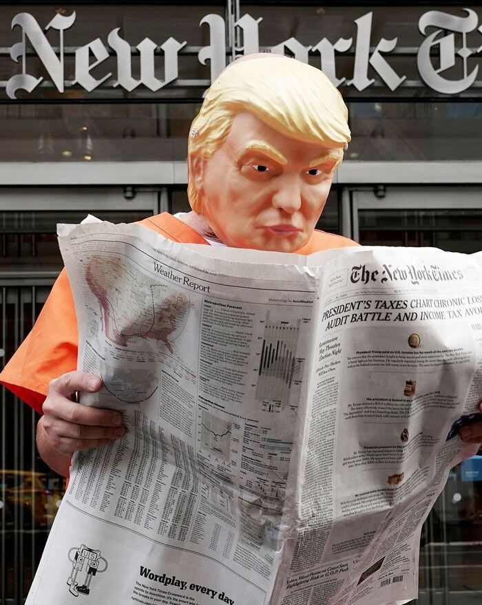 죄수복을 입은 도널드 트럼프 미 대통령으로 분장한 시민 운동가가 지난 28일(현지 시각) 미 뉴욕 맨해튼의 뉴욕타임스 사옥 앞에서 신문을 읽는 흉내를 내고 있다. /로이터 연합뉴스