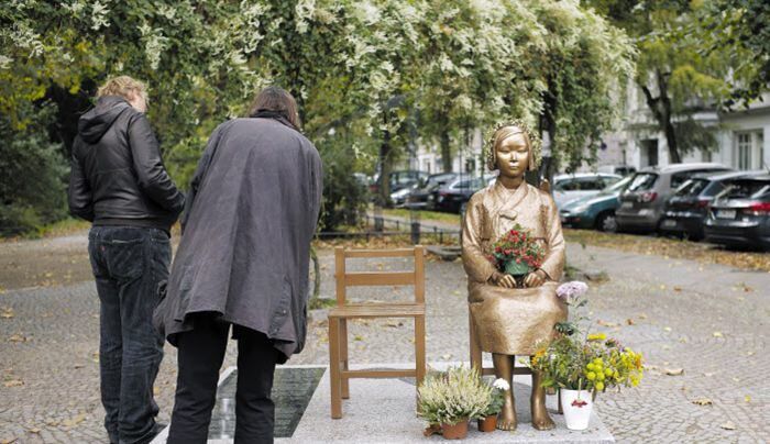 9일(현지 시각) 독일 베를린에서 시민들이 ‘평화의 소녀상’ 옆에 적힌 설명문을 읽고 있다. 독일 베를린시 미테구청은 지난 7일 소녀상 설치를 주관한 시민단체에 오는 14일까지 소녀상을 철거하라고 요구했다. /AP 연합뉴스