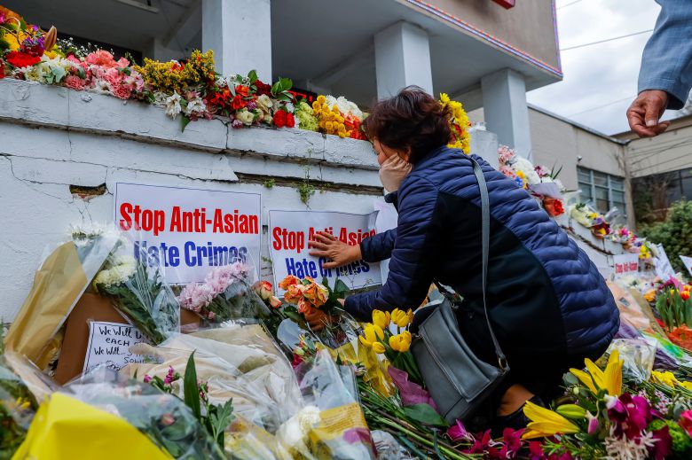 19일(현지 시각) 미 조지아주 애틀랜타 총격 범행 현장에 마련된 희생자 추모 공간에 한 시민이 '반(反)아시아계 증오 범죄를 멈춰라'라는 문구가 적힌 팻말을 놓고 있다. /EPA 연합뉴스