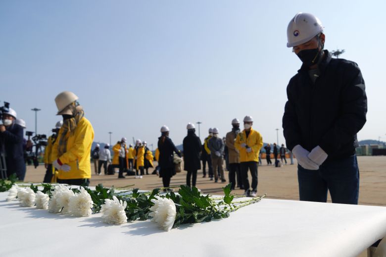 11일 오전 전남 목포시 목포신항에 인양된 세월호 선체 앞에서 세월호 참사 피해 가족들이 헌화와 묵념을 하며 피해자를 추모하고 있다. /연합뉴스