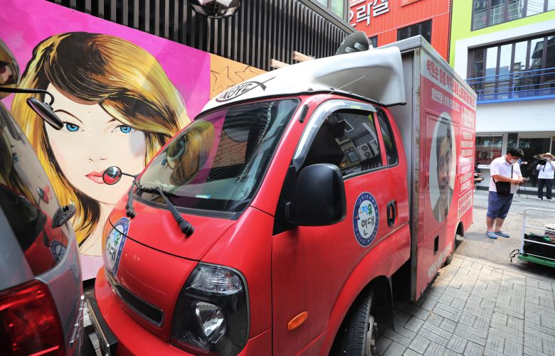 서울 종로구의 한 서점 외벽에 그려진 대권 주자 윤석열 예비후보의 부인 김건희 씨를 비방하는 내용의 벽화가 논란이 되고 있는 가운데, 2021년 7월 29일 보수 성향 단체 회원과 유튜버들이 벽화를 차로 막아놓고 시위를 하고 있다. / 오종찬 기자