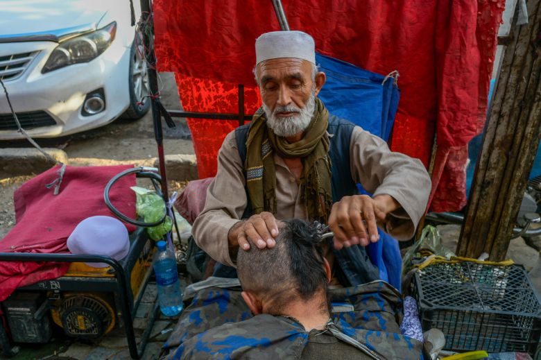 2021년 9월 22일 아프가니스탄 카불에서 한 거리 이발사가 한 남성의 머리를 깍아주고 있다./AFP 연합뉴스