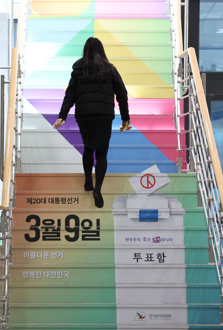 제20대 대통령 선거를 56일 앞둔 12일 경기 과천시 중앙선거관리위원회에서 직원이 선거 홍보 문구와 그림이 래핑 처리된 계단을 오르고 있다. /연합뉴스