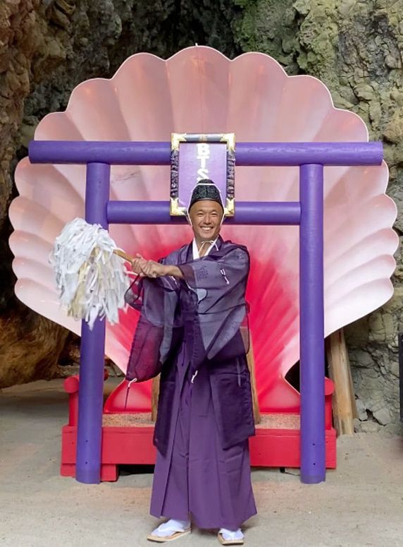 BTS신사의 특별기도를 소개한 사진. 신주(신사에서 일하는 사람) 뒤로 'BTS' 글자가 보인다. 보라색 옷을 입은 신주가 참여하는 특별기도에는 최소 5000엔을 내야 한다. 보라색은 BTS를 상징하는 색이다. /BTS신사 공식 홈페이지