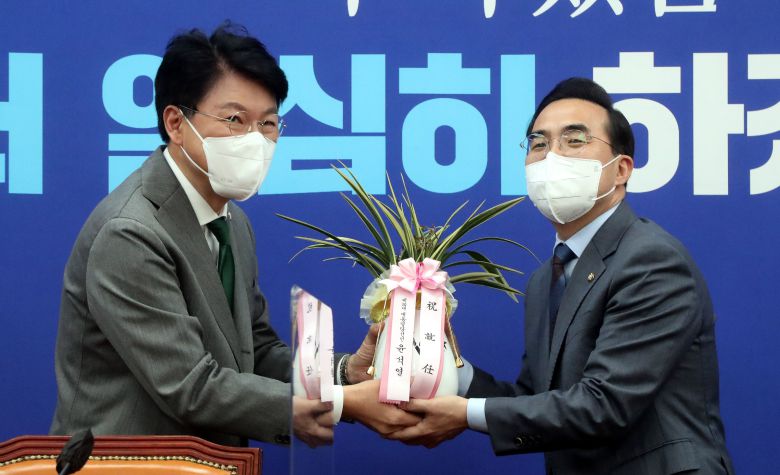 더불어민주당 박홍근 신임 원내대표(오른쪽)가 25일 서울 여의도 국회 원내대표 회의실에서 장제원 대통령 당선인 비서실장으로부터 윤석열 대통령 당선인의 축하 난을 받고 있다./연합뉴스