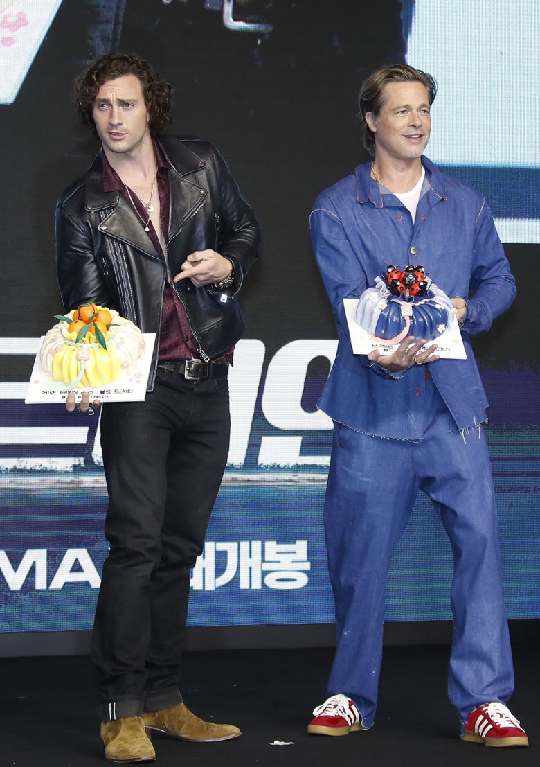 할리우드 배우 애런 테일러 존슨과 브래드 피트가 내한 기자회견에서 복주머니 케이크를 받고 기뻐하고 있다. /뉴스1