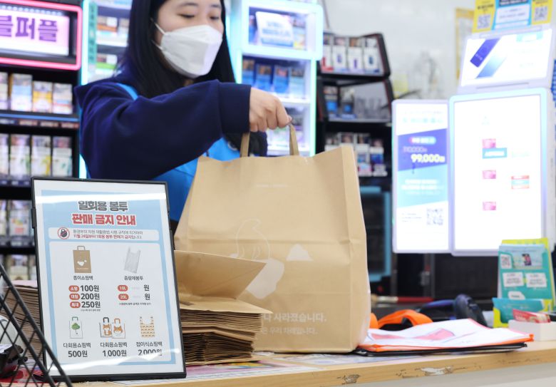 편의점 일회용 비닐봉투 판매, 식당 종이컵·플라스틱 빨대 사용이 금지된 24일 서울의 한 편의점에서 직원이 손님이 온라인으로 주문한 물품을 종이봉투에 담아 정리하고 있다. /연합뉴스
