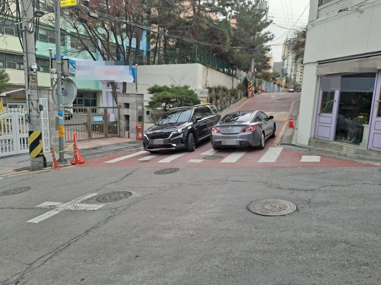 지난 2일 오후 방과후 수업을 마치고 하교하던 초등학생이 음주 차량에 치여 숨지는 사고가 발생한 가운데, 이 사고가 난 초등학교 후문 인근 인도조차 없는 도로에서 차량 2대가 힘겹게 지나치고 있다./강우량 기자