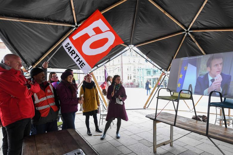 22일(현지 시각) 프랑스 서부 도시 르망에서 연금 개혁에 반대하는 시위대가 에마뉘엘 마크롱 프랑스 대통령의 TV 인터뷰를 보고 있다. /AFP 연합뉴스