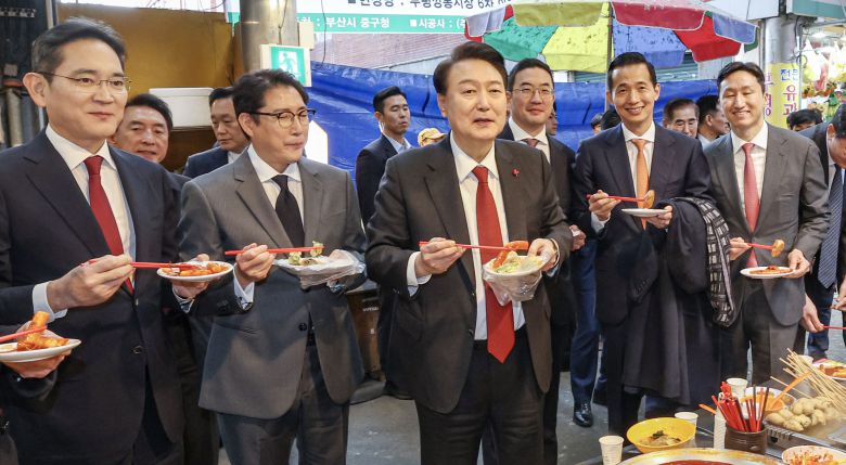 윤석열 대통령이 6일 부산 중구 깡통시장을 방문해 이재용 삼성전자 회장, 구광모 LG그룹 회장, 조현준 효성그룹 회장, 김동관 한화그룹 부회장, 최재원 SK수석부회장 등 기업총수들과 함께 떡볶이 등을 맛보고 있다./뉴스1