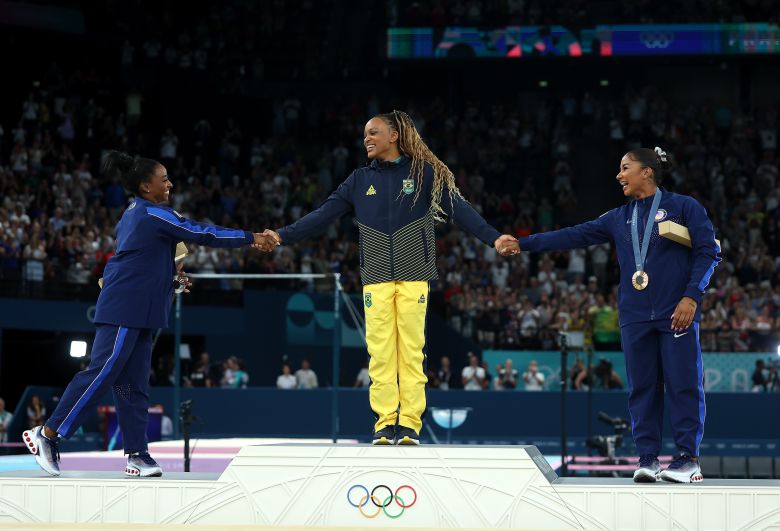 5일 파리올림픽 여자 기계체조 마루운동 시상식에서 각각 금·은·동메달을 딴 레베카 안드라데(가운데), 시몬 바일스(왼쪽), 조던 차일스가 손을 잡고 서로를 축하하고 있다. /연합뉴스