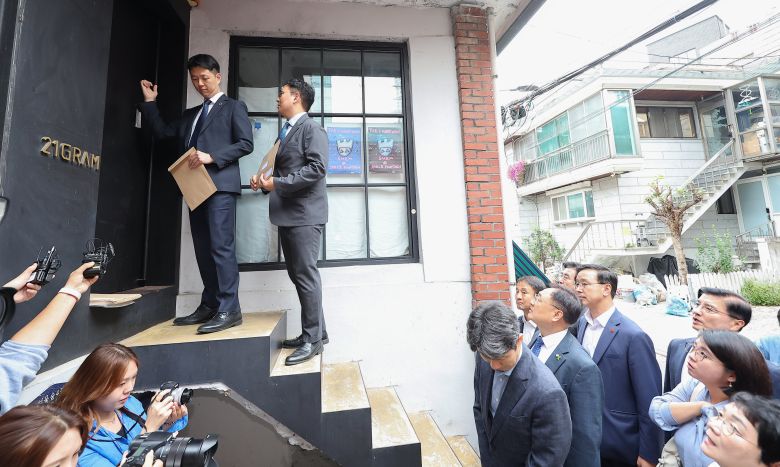 국회 행정안전위원회 소속 입법조사관과 국회사무처 의회경호담당관실 관계자가 7일 오후 서울 성동구에 있는 실내 건축 업체 ‘21그램’ 사무실 앞에서 국회 국정감사에 증인으로 출석할 것을 명령하는 동행명령장 집행을 위해 문을 두드리고 있다. 21그램은 이전되는 대통령 관저의 인테리어 공사를 수주했으나, 일부를 무자격 업체에 불법 하도급한 것으로 감사원 감사에서 확인됐다. 21그램은 김건희 여사가 운영했던 회사 코바나컨텐츠의 행사를 후원한 이력이 있는 것으로 알려졌다. 야당은 이날 국정감사 증인으로 채택한 21그램 대표 김태영·이승만씨가 불출석하자 두 사람에 대해 동행명령장을 발부했다. /연합뉴스