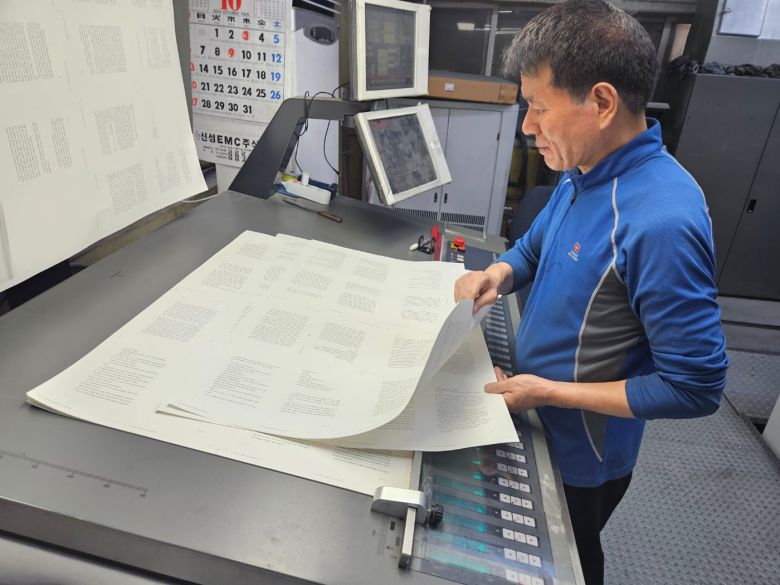 12일 파주출판단지 인근 천광인쇄소 직원 전대근(64)씨가 인쇄된 종이를 들어다보며 상태를 확인하고 있다. /황지윤 기자