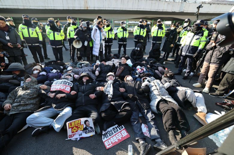 Members of conservative groups and supporters of South Korean President Yoon Suk-yeol lie on the ground in front of the entrance to the presidential residence in Yongsan District, Seoul, on Jan. 2, 2025, in defiance of police orders to disperse./News1