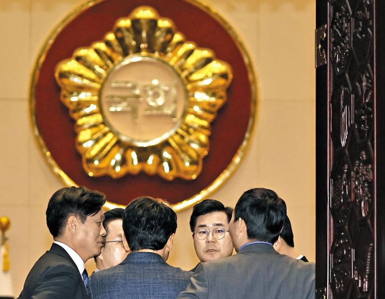 더불어민주당 의원들이 국회 본회의장에 모여 대화를 나누는 모습. 민주당은 지난 21일 여론조사 업체 관리·통제를 강화하는 법안을 발의했다. /연합뉴스