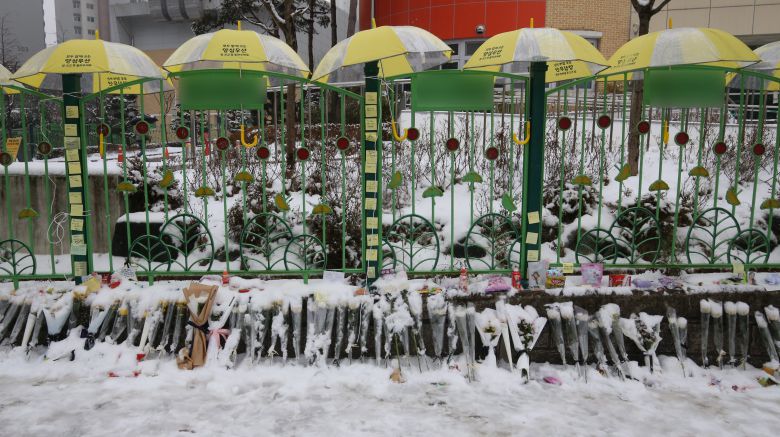 대전 초등학생 피살사건이 발생한 대전 서구의 한 초등학교 정문에 추모객들이 놓고 간 국화와 편지 위에 우산이 설치돼 있다. /뉴스1