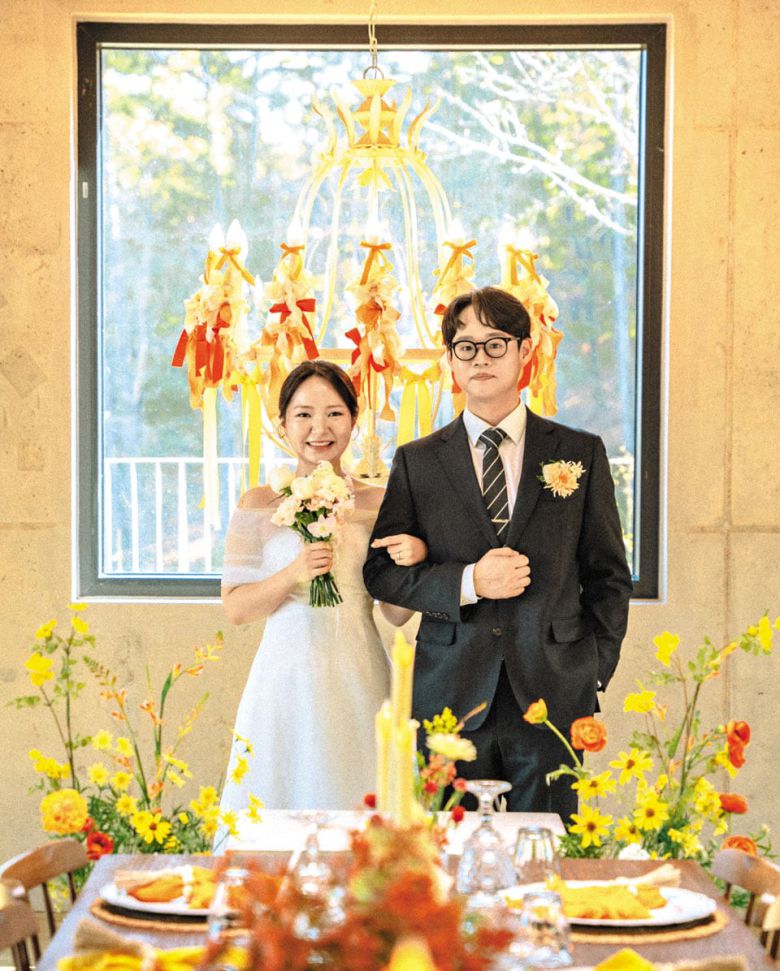 Cho Ha-jung (left) poses with her husband Yoo Ji-hyun just before their wedding last November at a rental venue in Yongin, Gyeonggi Province, in this photo provided by Cho. Twelve immediate family members attended the ceremony, sharing a meal at a flower-decorated table. The bride’s older brother served as the emcee.