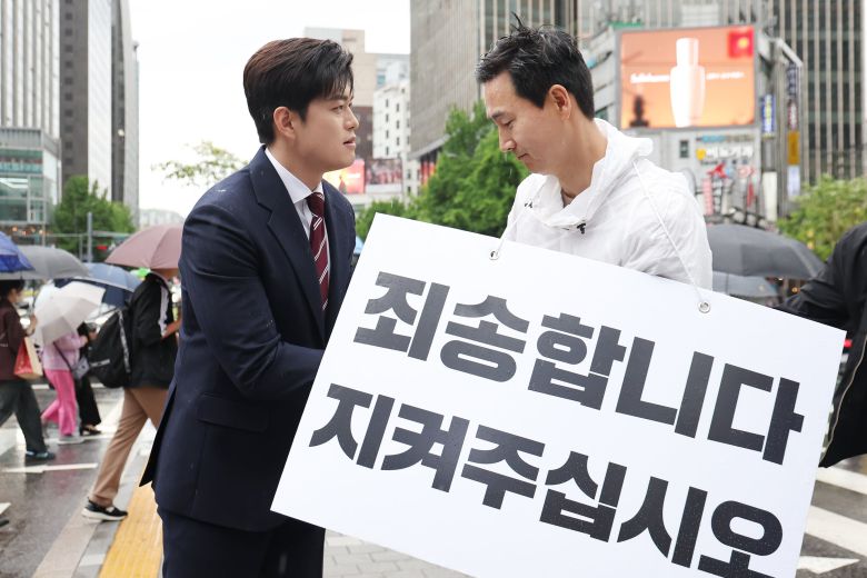 김용태(왼쪽) 국민의힘 비상대책위원장이 16일 서울 광화문광장에서 국민의힘 지지를 호소하는 내용의 팻말을 들고 있는 김기흥 전 대통령실 부대변인을 격려하고 있다./뉴스1