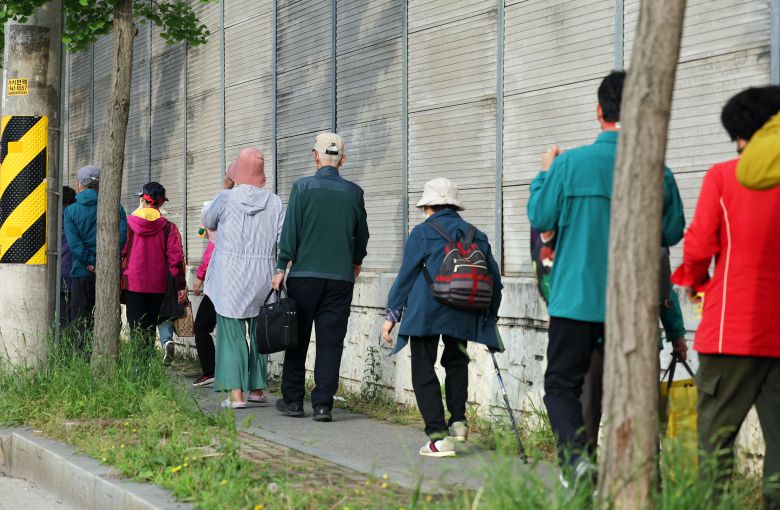 금호타이어 광주공장 화재가 발생한 17일 오후 광주 광산구 소촌동 한 아파트 인근 도로에서 주민들이 대피소로 가는 버스를 기다리고 있다. 광주시와 광산구는 화재로 발생하는 검은 연기의 직접적인 영향을 받는 인접 4개 아파트 단지 주민들을 위해 광주여자대학교 체육관에 대피소를 마련했다./연합뉴스