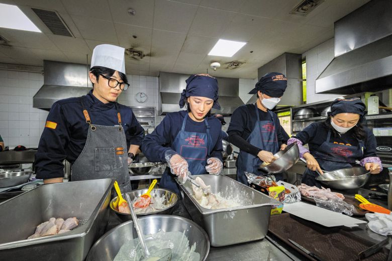 다른 예비 치킨집 사장들과 함께 교육 받은 본지 정시행 기자(왼쪽에서 두 번째)가 반죽옷 입힌 닭을 튀김 가루 트레이에 옮겨담고 있다. 튀기는 시간 10분을 포함, 주문 받은 지 15분 만에 배달로 넘겨야 한다. 위생 마스크는 사진 촬영 때만 잠시 벗었다. /이건송 영상미디어 기자