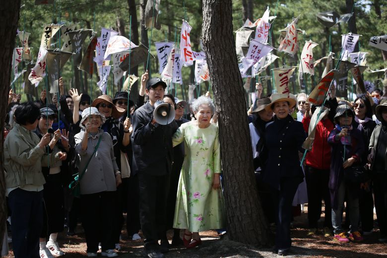 25일 강릉 순포해변 영화 '청명과 곡우 사이' 촬영 현장의 유준상 감독(가운데 확성기 든 사람)과 주연 배우 박정자(유 감독 오른쪽 꽃무늬 원피스). '조문객' 150여명이 든 만장엔 배우 박정자의 출연작 제목이 적혀 있다./강릉=이태훈 기자