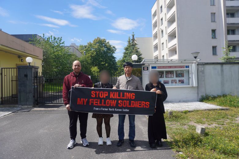 지난 20일(현지 시각) 오후 폴란드의 수도 바르샤바의 북한 대사관 앞에서 북한 군인 출신 엄영남(오른쪽에서 두번째)씨와 케이시 라티그(가장 왼쪽) FSI 공동대표가 ‘STOP KILLING MY FELLOW SOLDIERS(내 동료 군인들을 죽이지 마라)’라고 적힌 플래카드를 들고 있다. 엄씨와 동행한 두 여성은 본인 요청에 따라 얼굴이 블러 처리됐다./FSI 제공