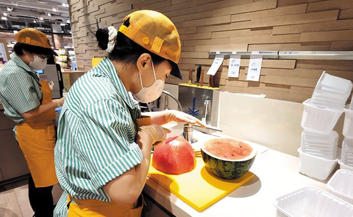 서울 시내 백화점 지하 식품관의 서비스 코너 직원들이 고객이 산 통수박을 손질해주고 있다. 수박은 거의 절반이 껍질. 음식쓰레기를 극도로 꺼리는 소비자들은 수박 값을 더 내더라도 껍질을 대신 처리해주는 쪽을 원한다./현대백화점