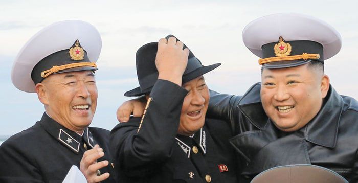 북한 김정은이 2022년 함경남도의 채소 생산 기지를 방문해 김명식(가운데) 해군사령관과 모자를 바꿔 쓰고 기념 촬영을 하고 있다. /조선중앙통신 연합뉴스