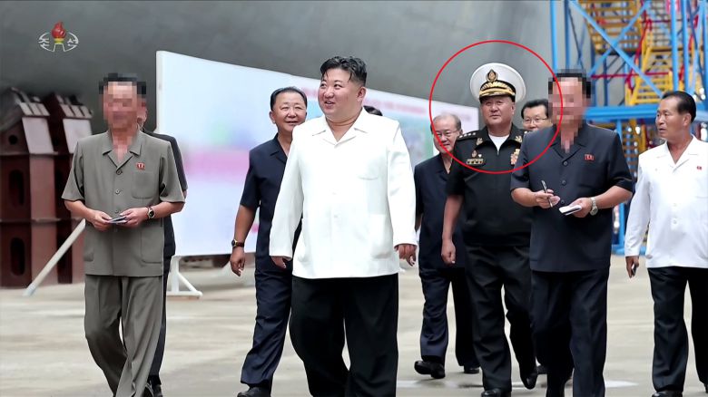북한 조선중앙TV가 29일 방영한 기록영화 '위민헌신의 여정, 새로운 변혁의 2024년'에 김명식 전 해군사령관(빨간색 동그라미)의 모습이 삭제되지 않은 채 등장했다. 북한은 앞서 지난 13일 방영한 구축함 '강건호' 진수기념식 영상에서 김정은 국무위원장의 지난 3월 함선건조사업 현지시찰 사진을 재공개하면서 당초 김 위원장과 함께 있던 김명식 전 해군사령관을 완전히 삭제한 채 편집해 내보냈다. /조선중앙TV 연합뉴스