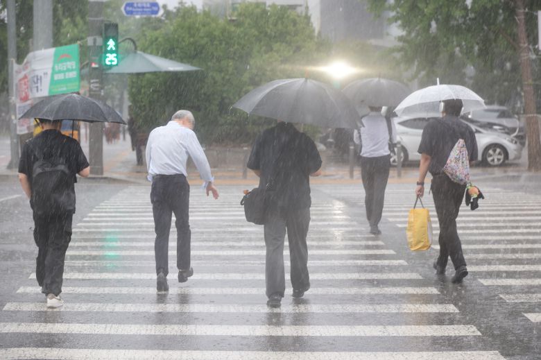 People walk in the rain near the National Assembly in Yeouido, Seoul, on July 8, 2025./Yonhap