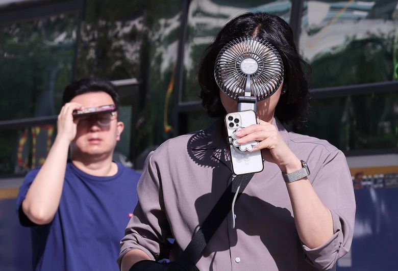 폭염이 연일 이어지는 10일 서울 종로구 광화문광장 인근에서 한 시민이 손선풍기를 얼굴에 대며 출근하고 있다. /뉴스1