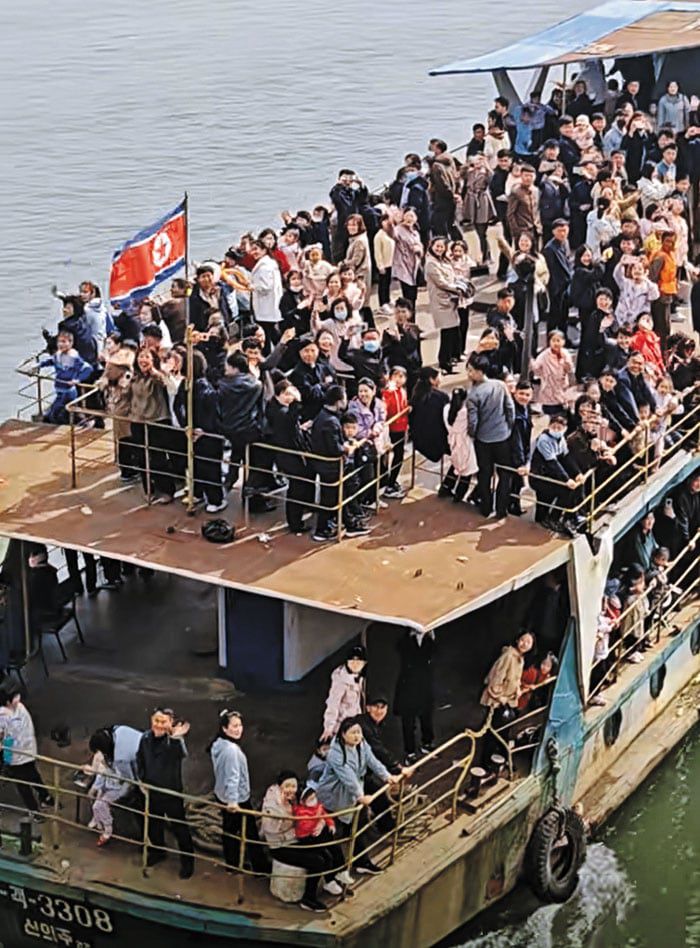 North Korean residents wave toward Dandong, China, from a cruise ship crossing the Yalu River from Sinuiju in April 2025./Douyin