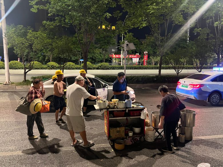 17일 새벽 중국 우한의 택시 기사(흰 옷)가 안전모를 쓴 일용직 노동자들 사이에서 값싼 죽으로 끼니를 때우고 있다./우한=이벌찬 특파원