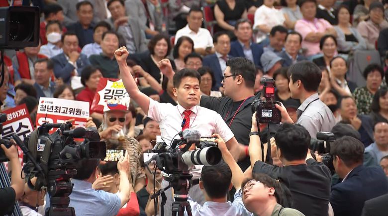 유튜버 전한길씨가 8일 대구 북구 엑스코에서 열린 국민의힘 전당대회에서 취재진에 둘러싸여 주먹 쥔 손을 들어 보이고 있다. 이날 전씨는 김근식 최고위원 후보 연설 도중 당원들에게 “배신자”를 연호하도록 독려했다./TV조선