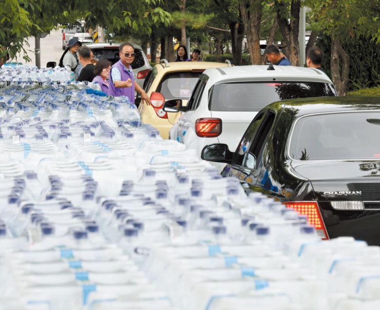 강릉, 생수 ‘드라이브 스루’ - 5일 강원 강릉시 포남2동 주민센터 근처에서 자원봉사자들이 생수를 나눠주고 있다. 차에 실어 가기 좋도록 ‘드라이브스루’ 방식으로 생수를 배급했다. 생수를 받아 가려는 차량이 줄지어 서 있다. 가뭄에 시달리고 있는 강릉시는 이날 시민들에게 1인당 12L씩 생수를 배급했다. /장경식 기자
