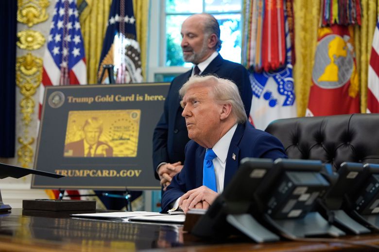 트럼프 대통령이 19일 워싱턴 백악관 오벌 오피스에서 하워드 러트닉 상무장관 함께 기자들의 질문을 듣고 있다. 옆에 골드카드 시안이 놓여져 있다. /AP 연합뉴스