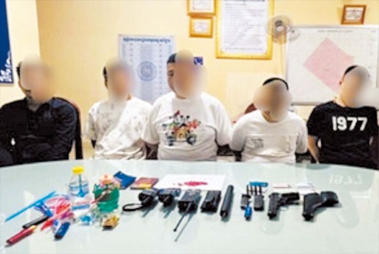 지난달 말 캄보디아 프놈펜에서 50대 한국인을 납치∙고문한 중국인 4명과 캄보디아인 1명이 현지 경찰에 붙잡혀 앉아있다. 이들 앞에는 경찰이 압수한 권총과 무전기 등이 놓여있다./캄보디아 경찰