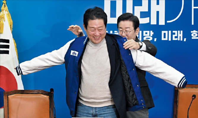 조선일보DB22대 총선을 두 달 앞둔 2024년 2월 14일 이재명 당시 민주당 대표가 유동철 동의대 교수에게 당 점퍼를 입혀주고 있다.